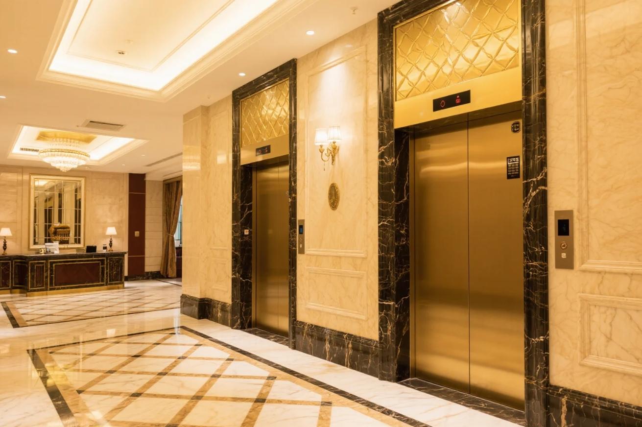 Five-star hotel corridor with gold-trimmed marble elevator doors