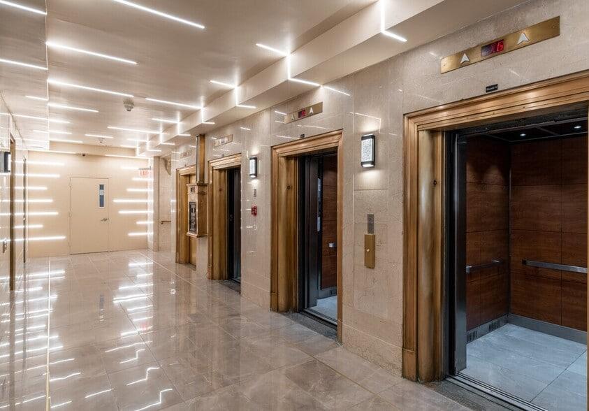 Heritage hotel corridor with brass-trimmed elevator doors and digital directory